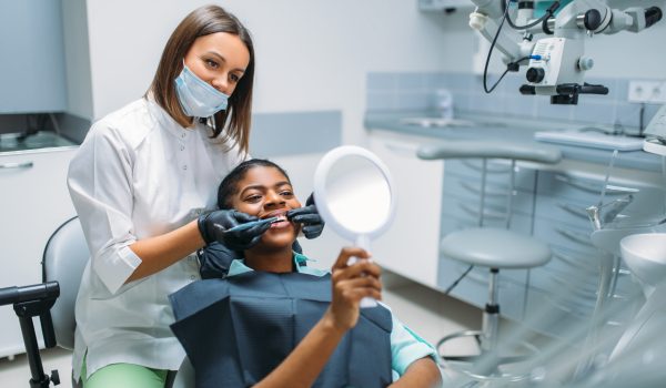 Dentist shows teeth to client. Female patient on whitening procedure in dental clinic. Woman in dentistry cabinet, stomatology